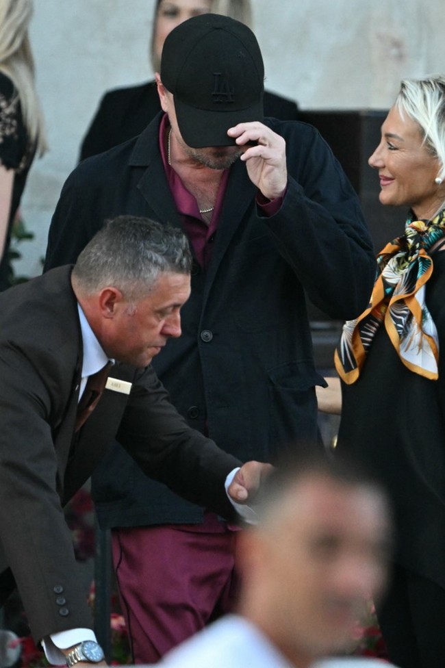 Keesokan harinya, Leonardo kembali muncul dengan topi yang sama. Kali ini, pria 50 tahun itu memakai satu set busana berwarna merah yang dengan blazer hitam sebagai luaran. (Foto: Stefano Rellandini/AFP)