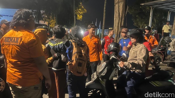 Kerumunan warga menyaksikan proses pencarian pemuda yang loncat ke Sungai Brantas di Dam Rolak Songo, Mojokerto.