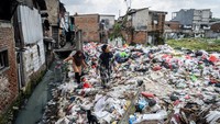 Warga berjalan di tumpukan sampah di Kampung Kiapang, Palmerah, Jakarta, Selasa (2/7/2025). Sampah didominasi limbah rumah tangga. Foto: ANTARA FOTO/Bayu Pratama S