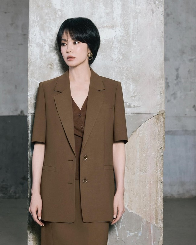 Bintang drama Korea ‘The Glory’ ini memadukan blazer cokelat lengan pendek dengan inner top bernuansa senada plus rok lurus. Kesannya sleek, minimalis, tapi tetap powerful. Potongan blazer yang sedikit longgar membuat look ini terkesan modern. Foto: Instagram/@kyo1122 @michaachannel