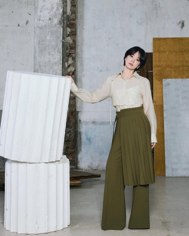 Gaya Song Hye Kyo ini terkesan edgy, fresh dan artsy. Wanita 43 tahun ini memadukan sheer blouse krem dengan inner bertekstur serta celana olive high-waist model pleats. Look ini bikin kamu tampak sophisticated, apalagi jika kantor kamu punya dress code smart casual. Foto: Instagram/@kyo1122 @michaachannel