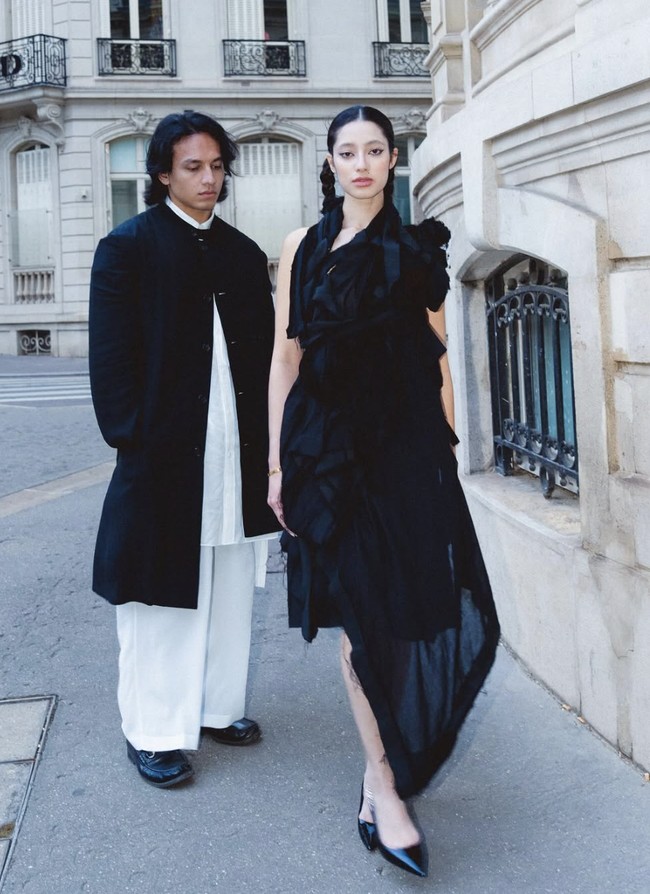 Saat menghadiri fashion show Yohji Yamamoto, pasangan ini tampil penuh karakter. Ameera, influencer asal Malaysia itu mencuri perhatian dengan dress hitam asimetris bergaya avant-garde dan rambut dikepang dua yang memberi kesan fierce. Foto: dok. Instagram @littlemisskhan