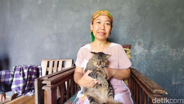 Siti sedang memegang kucing peliharaannya yang menyelamatkannya dari bahaya ular King Kobra.