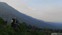 Beberapa orang sedang duduk sambil menikmati keindahan Gunung Ciremai dari ketinggian