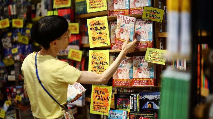 A member of staff places the comic book titled The Future I saw, authored by manga artist Ryo Tatsuki, on the shelf at Village Vanguard book store in Tokyo, Japan June 30, 2025. REUTERS/Issei Kato/File Photo Purchase Licensing Rights