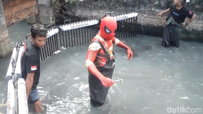 Spiderman Parepare membantu pemasangan besi penjaring sampah di kanal laut.