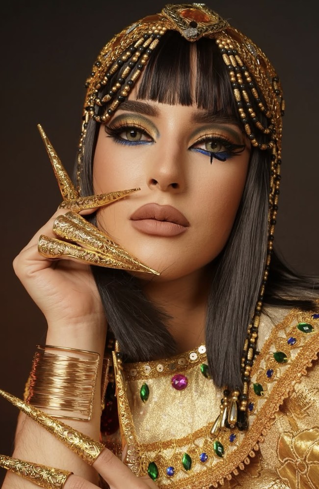 Tasya Farasya tampil dalam interpretasi Cleopatra yang glamor dan tajam. Makeup matanya didominasi warna emas metalik yang menyala, dipadu gradasi gelap di bagian crease dan aksen biru elektrik di bawah mata, menciptakan efek mata yang hidup dan berani. Foto: dok. Instagram @tasyafarasya @ttasyiiathasyia