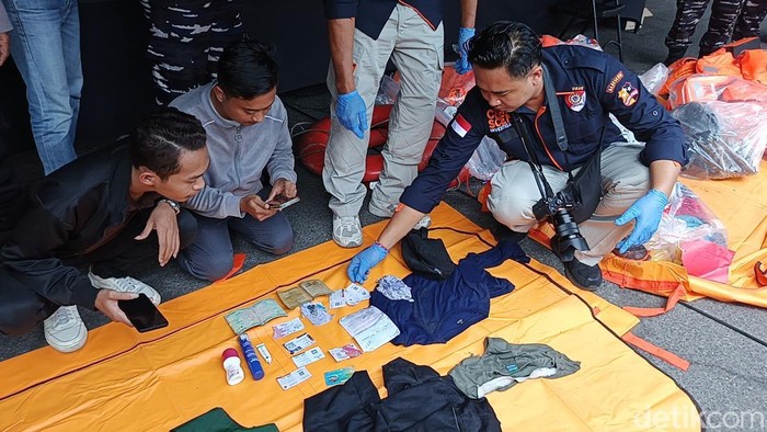 Adik Ahmad Rifai (34) salah seorang korban kapal tenggelam di Selat Bali saat melakukan pengecekan barang-barang milik korban di Pelabuhan Gilimanuk, Bali, Sabtu (5/7/2025). (I Putu Adi Budiastrawan/detikBali).