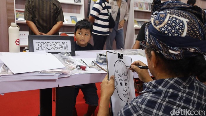 Suasana keramaian pengunjung di PKB 2025 yang menunggu giliran disketsa wajahnya oleh empat seniman karikatur di Art Center Denpasar, Sabtu (5/7/2025). (Aryo Mahendro/detikBali)