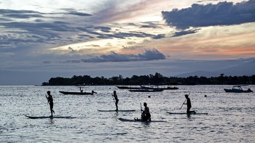 Sejumlah wisatawan asing bermain paddel board atau papan dayung di kawasan taman wisata perairan Gili Matra di Gili Trawangan, Desa Gili Indah, Kecamatan Pemenang, Tanjung, Lombok Utara, NTB, Sabtu (5/7/2025). Kawasan konservasi nasional taman wisata perairan (TWP) Gili Air, Gili Meno dan Gili Trawangan atau yang lebih dikenal dengan Gili Matra memiliki potensi alam bahari yang indah, antara lain hamparan pasir putih dan lautnya yang jernih serta terumbu karang  dengan ikan yang beranekaragam yamg mampu menarik wisatawan baik lokal maupun mancanegara.
ANTARA FOTO/Ahmad Subaidi