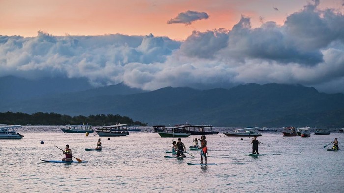 Sejumlah wisatawan asing bermain paddel board atau papan dayung di kawasan taman wisata perairan Gili Matra di Gili Trawangan, Desa Gili Indah, Kecamatan Pemenang, Tanjung, Lombok Utara, NTB, Sabtu (5/7/2025). Kawasan konservasi nasional taman wisata perairan (TWP) Gili Air, Gili Meno dan Gili Trawangan atau yang lebih dikenal dengan Gili Matra memiliki potensi alam bahari yang indah, antara lain hamparan pasir putih dan lautnya yang jernih serta terumbu karang  dengan ikan yang beranekaragam yamg mampu menarik wisatawan baik lokal maupun mancanegara.
ANTARA FOTO/Ahmad Subaidi