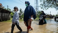 Warga menembus genangan air di Desa Gaga, Tangerang, saat banjir melanda akibat luapan Sungai Cisadane, Minggu (6/7/2025). ANTARA FOTO/Putra M. Akbar
