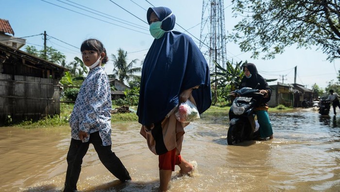 Warga memandang kondisi di depan rumahnya nan tergenang banjir di Desa Gaga, Pakuhaji, Kabupaten Tangerang, Banten, Minggu (6/7/2025). Banjir dengan ketinggian 15 - 30 cm tersebut disebabkan meluapnya Sungai Cisadane nan dipicu air kiriman dari wilayah Bogor dan tingginya curah hujan pada Sabtu (5/7). ANTARA FOTO/Putra M. Akbar/rwa.