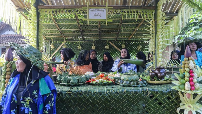 Warga membawa bubur suro dan penganan lain saat kirab pada Festival Bubur Suro di Desa Wisata Bandung, Banjar, Kabupaten Pandeglang, Banten, Minggu (6/7/2025). Festival tahunan yang menghadirkan beragam kegiatan, di antaranya pentas seni, lomba pakaian adat, dan kompetisi memasak bubur suro yang dilanjutkan dengan kirab tersebut digelar dalam rangka memperingati Hari Asyura (10 Muharram) 1447 Hijriah sekaligus upaya mempererat kebersamaan antar warga. ANTARA FOTO/Angga Budhiyanto/rwa.