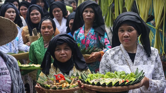 Warga membawa bubur suro dan penganan lain saat kirab pada Festival Bubur Suro di Desa Wisata Bandung, Banjar, Kabupaten Pandeglang, Banten, Minggu (6/7/2025). Festival tahunan yang menghadirkan beragam kegiatan, di antaranya pentas seni, lomba pakaian adat, dan kompetisi memasak bubur suro yang dilanjutkan dengan kirab tersebut digelar dalam rangka memperingati Hari Asyura (10 Muharram) 1447 Hijriah sekaligus upaya mempererat kebersamaan antar warga. ANTARA FOTO/Angga Budhiyanto/rwa.