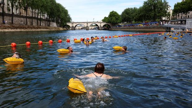 Orang-orang berenang di Sungai Seine di lokasi Bras Marie, dibuka untuk perenang yang menandai sesi pemandian umum pertama di jalur air bersejarah ibu kota, di Paris, Prancis, 5 Juli 2025. (REUTERS/Abdul Saboor)