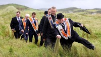 Anggota Orde Oranye berjalan menyusuri pantai Rossnowlagh dalam pawai tahunan di County Donegal, Irlandia, Sabtu (5/7/2025). REUTERS/Cathal McNaughton