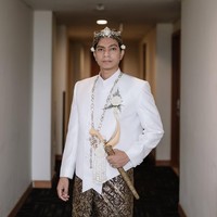 Adapun Dio Novandra, yang merupakan warga Medokan, Rungkut Surabaya, memakai beskap putih berpadu batik motif klasik. Tidak ketinggalan blangkon, dan keris sebagai aksesori pelengkap. (Foto: Instagram/@estoria_photography)