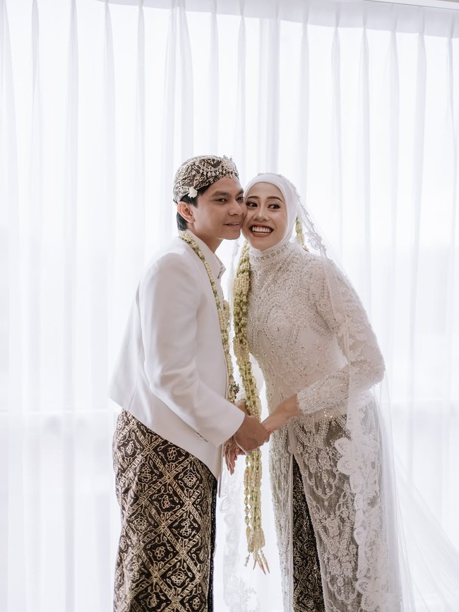 Busana pengantin Jawa yang didominasi warna putih menjadi pilihan kedua sejoli ini untuk hari bahagia mereka. Biasa bergaya sporty di lapangan, Megawati yang mendapat julukan Megatron itu tampil beda dengan kebaya panjang penuh detail brokat yang  menawan. (Foto: Instagram/@estoria_photography)