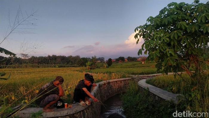Warga memancing di aliran Sungai Cibondol dengan latar Gunung Ciremai.