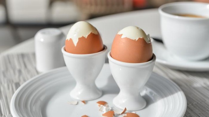 Boiled eggs in egg cup on a white plate