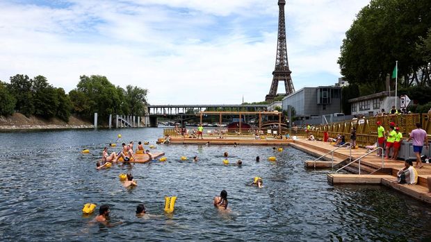 Berenang di Sungai Seine Dekat Eiffel Kini Jadi Kenyataan People swim in the River Seine, with the Eiffel tower in the background, at the Grenelle site, opened to swimmers marking the first public bathing session in the capital's historic waterway, in Paris, France, July 5, 2025. REUTERS/Abdul Saboor TPX IMAGES OF THE DAY