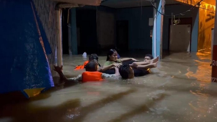 Polisi dan TNI membantu mengevakuasi ibu hamil yang hendak melahirkan di tengah banjir Kebon Pala, Jaktim, Minggu (6/7/2025) malam.