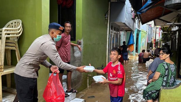 Polisi turun membantu penduduk terdampak banjir di Kebon Pala, Jakarta Timur, Senin (7/7/2025). Polisi mendirikan dapur lapangan hingga pelayanan kesehatan kepada penduduk tedampak banjir.