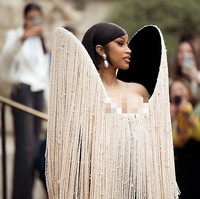 Gaun dilengkapi aksen bahu super besar yang dihiasi untaian manik-manik gading. Untaian manik-manik itu menjuntai hingga lutut, nyaris menutupi sarung tangan opera hitam yang melengkapi total look-nya. Foto: WireImage/Christian Vierig