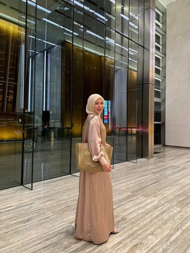 Gaya Ayana Moon pakai gamis warna navy dan hijab segi empat warna cream.