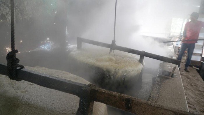 Pekerja memindahkan gula tebu masak ke tampi besar untuk proses pengeringan alami di sentra pengolahan gula tebu rumahan di Desa Bendilwungu, Tulungagung, Jawa Timur, Senin (7/7/2025). Gula tradisional nonkristal atau biasa disebut gula garuk/awur untuk bahan baku kecap ataupun campuran bumbu petis ini dijual dengan harga saat ini di kisaran Rp980 ribuan per kuintal ke pasar Jombang, Madura dan Malang. ANTARA FOTO/Destyan Sujarwoko/rwa.