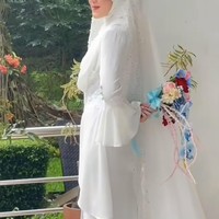Alya tampil anggun dengan busana pengantin putih berhijab. Gaun yang dikenakannya itu memiliki lengan berbentuk flare sleeves yang memberikan kesan feminin. Penampilannya lengkap dengan hijab putih polos yang dilapisi veil panjang berhias payet. Foto: Instagram/@gunawandwicahyo13