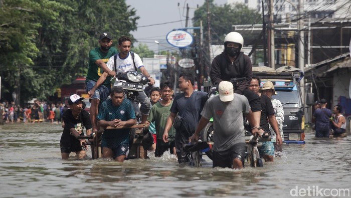 JalanΒ di Ciledug Banjir, Motor Diangkut Gerobak Warga membawa sepeda motor melintasi banjir di Jalan Hasyim Asy'ari, Ciledug, Tangerang, Selasa (8/7/2025).