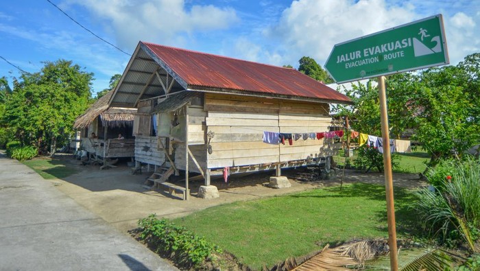 Warga melintas di dekat penanda jalur pemindahan tsunami di Desa Muara Siberut, Siberut Selatan, Kepulauan Mentawai, Sumatera Barat, Selasa (8/7/2025). Data BPBD Mentawai mencatat sebanyak 33 desa di Kepulauan Mentawai nan dihuni sekitar 50 ribu jiwa tetap berada di area rawan gempa dan tsunami akibat potensi gempa megathrust di segmen Siberut dengan 10 titik tempat pemindahan sementara (TES) dan 12 titik tempat pemindahan akhir (TEA) serta tiga jalur utama evakuasi. ANTARA FOTO/Iggoy el Fitra