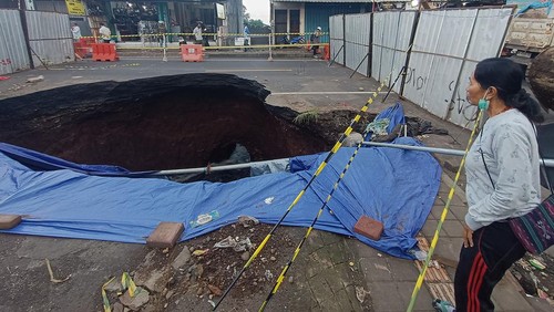Warga mengamati kondisi jalan amblas di jalur Denpasar-Gilimanuk, Desa Bajera, Tabanan, Bali, Selasa (8/7/2025). Jalur yang merupakan akses utama menuju ke Pulau Jawa tersebut sejak Senin (7/7) hingga saat ini ditutup akibat jalan amblas dengan kedalaman sekitar 6 meter dan menyebabkan kemacetan lalu lintas. ANTARA FOTO/Nyoman Hendra Wibowo
