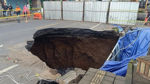 Warga mengamati kondisi jalan amblas di jalur Denpasar-Gilimanuk, Desa Bajera, Tabanan, Bali, Selasa (8/7/2025). Jalur yang merupakan akses utama menuju ke Pulau Jawa tersebut sejak Senin (7/7) hingga saat ini ditutup akibat jalan amblas dengan kedalaman sekitar 6 meter dan menyebabkan kemacetan lalu lintas. ANTARA FOTO/Nyoman Hendra Wibowo