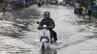 Pengendara menerobos banjir di Jalan Ceger Raya, Pondok Aren, Tangerang Selatan, Selasa (8/7/2025).