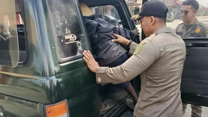 Satpol PP Bantul saat mengamankan pengemis yang kerap meresahkan di simpang empat Bakulan, Jetis, Bantul, Senin (7/7/2025).
