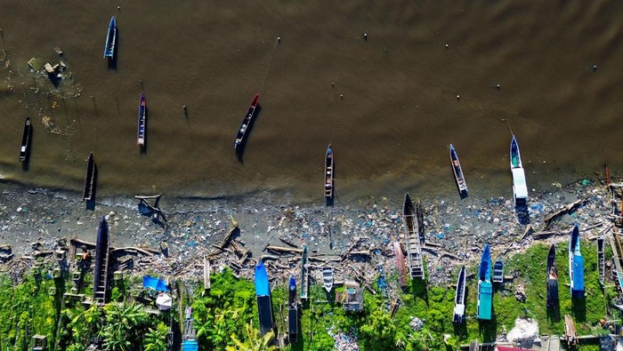 Nelayan mengeluarkan sampannya di antara sampah saat matahari terbit di Pantai Muara Siberut, Mentawai, Sumatera Barat, Selasa (8/7/2025). Pantai pulau terluar yang terkenal dengan keindahan alam dan ombaknya bagi peselancar itu dipenuhi sampah yang dibuang warga karena tidak tersedianya tempat pembuangan akhir serta sampah kiriman yang terbawa arus. ANTARA FOTO/Iggoy el Fitra/tom.