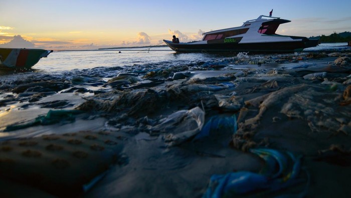 Nelayan mengeluarkan sampannya di antara sampah saat matahari terbit di Pantai Muara Siberut, Mentawai, Sumatera Barat, Selasa (8/7/2025). Pantai pulau terluar yang terkenal dengan keindahan alam dan ombaknya bagi peselancar itu dipenuhi sampah yang dibuang warga karena tidak tersedianya tempat pembuangan akhir serta sampah kiriman yang terbawa arus. ANTARA FOTO/Iggoy el Fitra/tom.