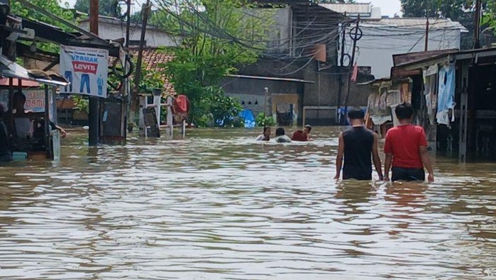 Warga melintas di genangan banjir yang melanda permukiman warga Kampung Cisereh, Desa Kadu Jaya, Curug, Kabupaten Tangerang. ANTARA/Azmi Samsul Maarif)