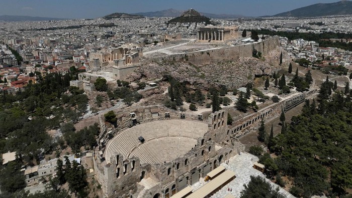 A woman uses a handheld electric fan while queuing to visit the Acropolis, during a heatwave with temperatures expected to overpass 40 degrees Celsius, in Athens, Greece, July 9, 2025. REUTERS/Stelios Misinas
