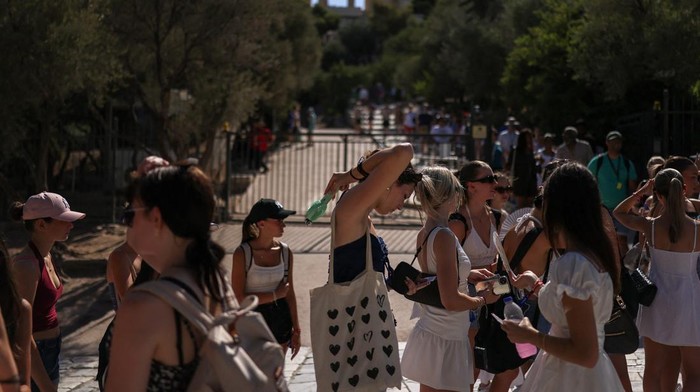 A woman uses a handheld electric fan while queuing to visit the Acropolis, during a heatwave with temperatures expected to overpass 40 degrees Celsius, in Athens, Greece, July 9, 2025. REUTERS/Stelios Misinas