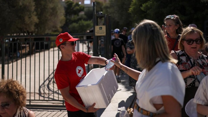 A woman uses a handheld electric fan while queuing to visit the Acropolis, during a heatwave with temperatures expected to overpass 40 degrees Celsius, in Athens, Greece, July 9, 2025. REUTERS/Stelios Misinas