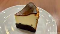 Jika ingin ngemil saja, kamu bisa pesan Basque Burnt Cheesecake (Rp 45 ribu). Bagian atasnya berupa cheesecake yang padat, lembut, dan gurih. Sedangkan bawahnya lapisan cokelat yang masih agak keras. Foto: Andi Annisa DR/detikFood