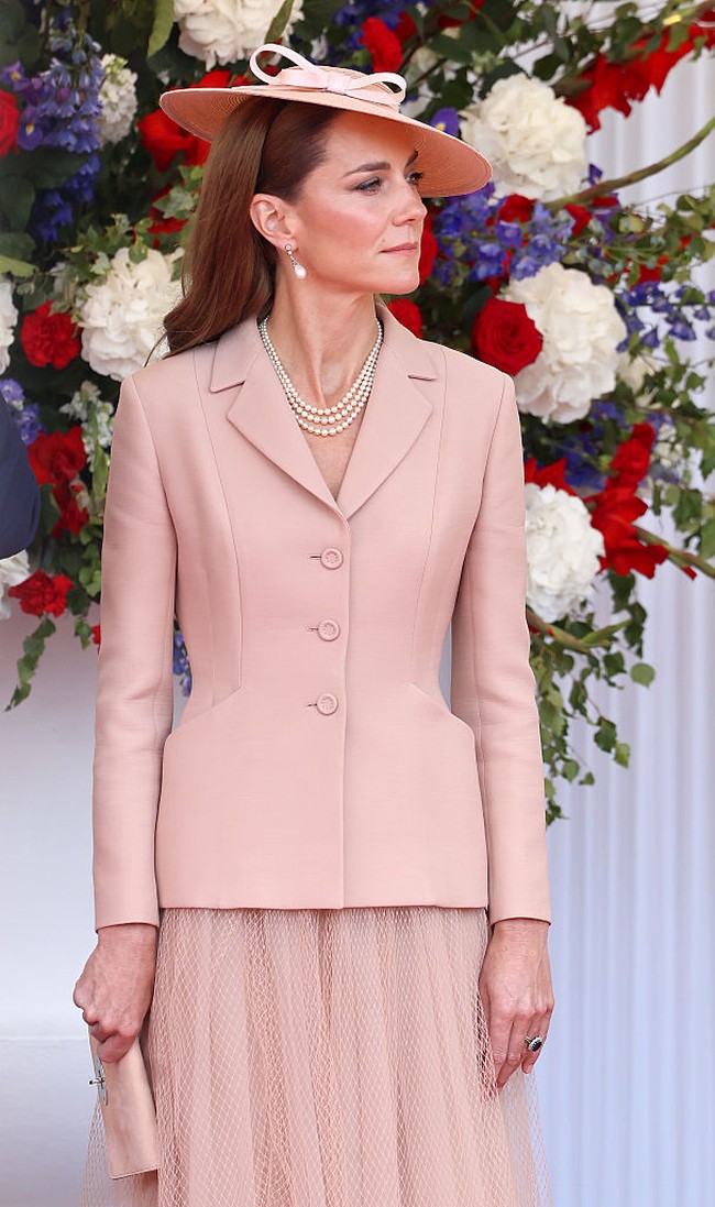 Tanggal 8 Juli menjadi momen penting ketika Kate menyambut Presiden Prancis Emmanuel Macron dan istrinya. Untuk pertama kalinya, ia tampil mengenakan busana Dior. Ini menjadi penampilan perdananya mengenakan busana dari rumah mode asal Prancis itu. Penampilannya dilengkapi anting mutiara Collingwood milik Putri Diana, topi merah muda dengan detail pita karya Jess Collett, serta kalung mutiara dari koleksi Ratu Elizabeth.  Foto: Chris Jackson/Getty Images