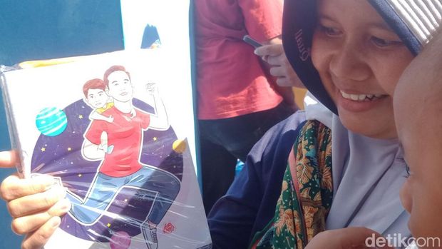 Salah satu warga saat mendapatkan buku yang dibagikan Wakil Presiden Gibran Rakabuming Raka di Rawa Jombor, Bayat, Klaten, Rabu (9/7/2025). Gibran di sana untuk menebar benih ikan nila.