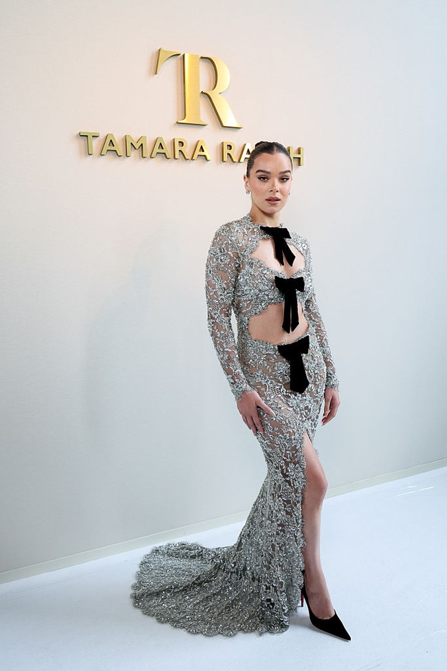 Sentuhan feminin dan sedikit vintage muncul lewat detail pita hitam yang menghiasi garis pinggang, dada, hingga leher gaun. Untuk melengkapi gayanya, Hailee memilih sepatau pump hitam berujung runcing dan clutch hitam sederhana. Dia tampil cukup minimalis dalam pemilihan aksesori, membiarkan gaun menjadi fokus utama penampilannya. Foto: Getty Images/Lyvans Boolaky,Jacopo Raule,Antoine Flament