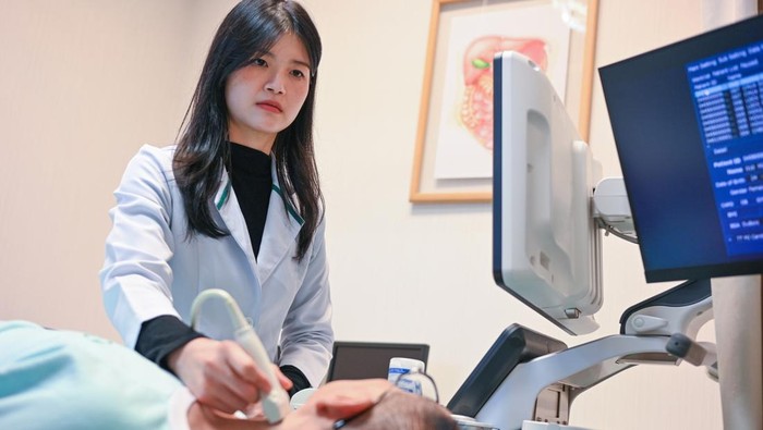 In a medical clinic, a doctor carefully moves an ultrasound probe over a patients throat, capturing real-time images for accurate diagnosis
