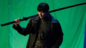 Lee Minho sebagai Yoo Joong Hyuk dengan pedang panjangnya di depan green screen. Di trailer film Omniscient Reader, green screen udah ganti jadi kota Seoul yang di ambang kehancuran. (Foto: dok. Lotte Cultureworks)